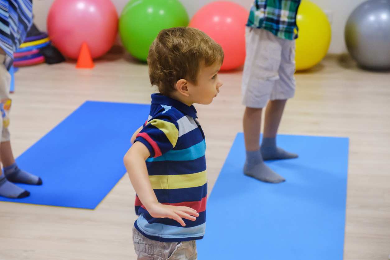 Cute sporty kid exercising on yoga mats in gym, children sport school concept Corsi Pomeridiani - Scuola Materna Peschiera Borromeo