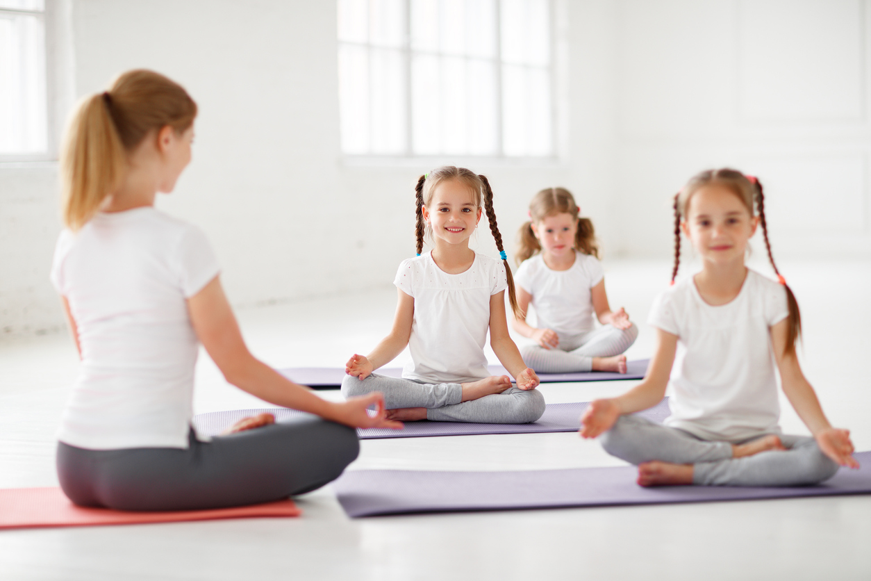 children practicing engaged in gymnastics and yoga with teacher Corsi Pomeridiani - Scuola Materna Peschiera Borromeo